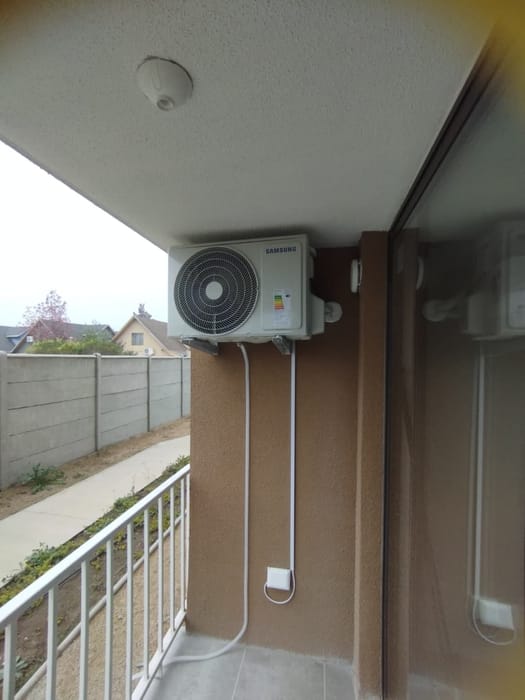 Unidad exterior de aire acondicionado instalada en el balcón de un departamento