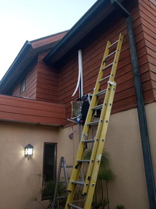 Técnico en escalera instalando la unidad exterior en la fachada de una casa