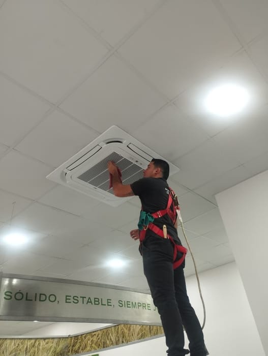 Técnico de Soloaire haciendo mantención a un equipo cassette en el cielo de una oficina