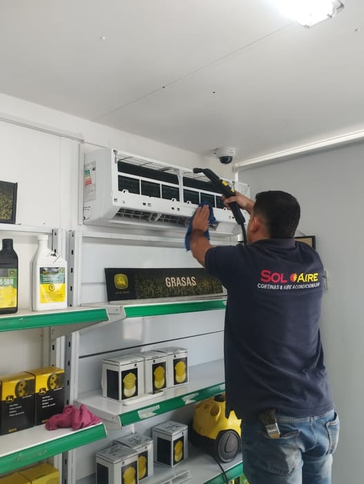 Técnico de Soloaire haciendo mantención a un split muro en un local comercial