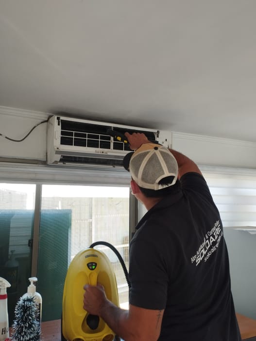 Técnico de Soloaire realizando la mantención de un split muro con equipo de limpieza