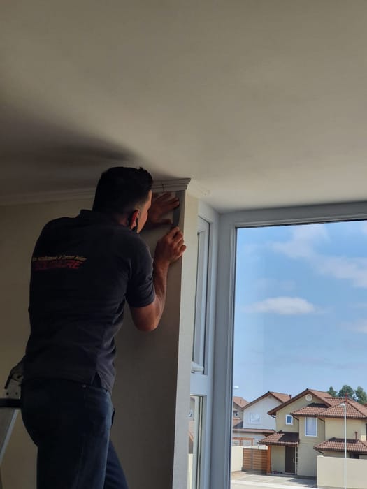 Técnico de Soloaire instalando una cortina roller junto a un ventanal