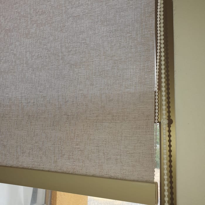 Detalle de la tela de una cortina roller beige instalada