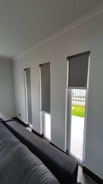 Cortinas roller instaladas en los ventanales de un living